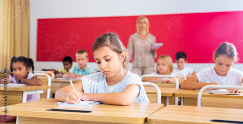 Portrait of girl who is posing at the desk in the classroom elementary school