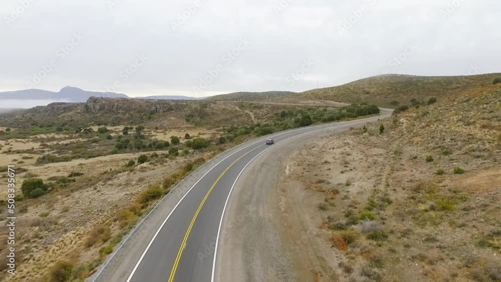 Rural highway. Traveling. Aerial view of the asphalt road across the yellow grassland and hills in an early foggy morning in autumn. 