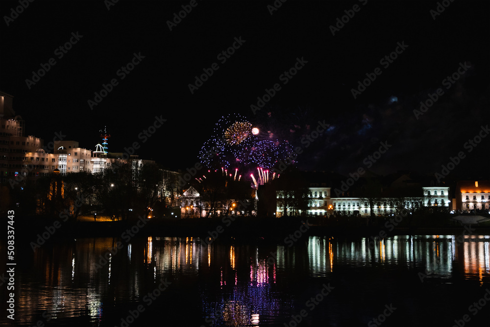 Simple orange firework over the ordinary European city at night near water. Amateur photo.
