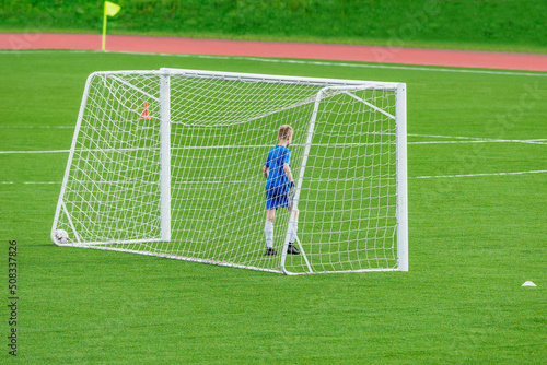 Young goalkeeper stands by the soccer gate.