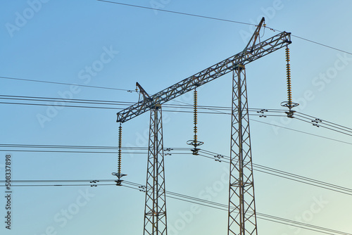 High voltage electricity tower with power line against blue sky. Overhead electric power line with insulators. Electricity generation, transmission, and distribution network. Indastry landscape.