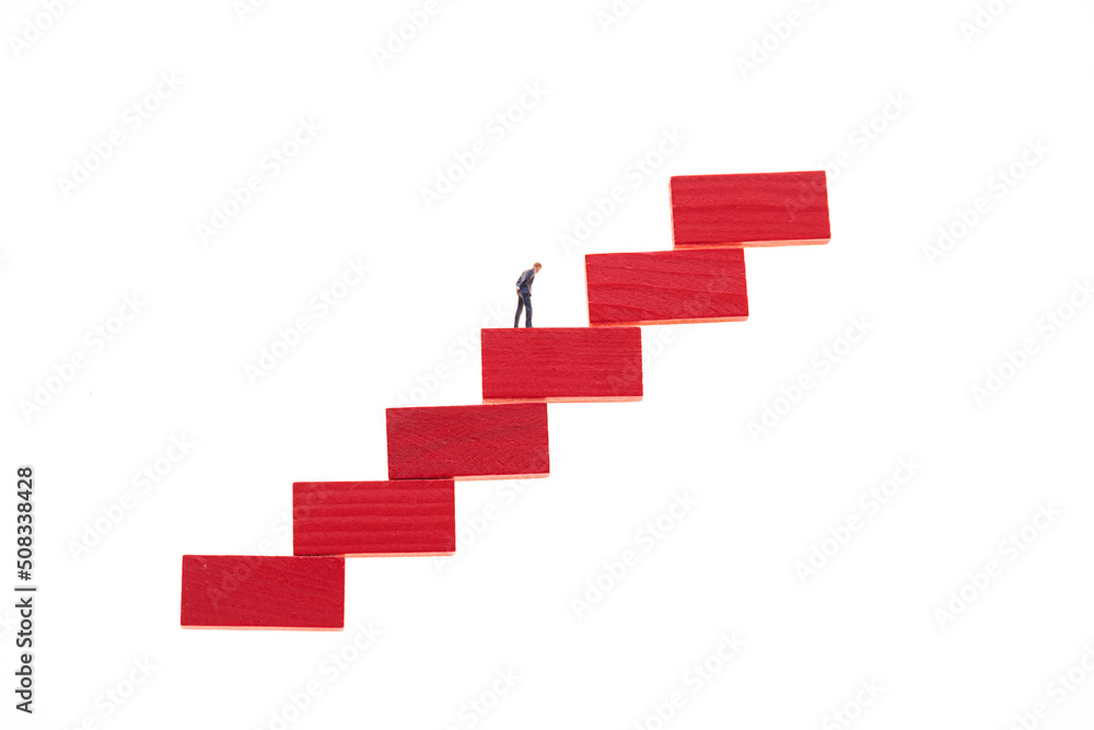 Career growth concept. Figurine of a businessman on a red step ladder isolated on a white background Career growth concept. Figurine of a businessman on a red step ladder isolated on a white background