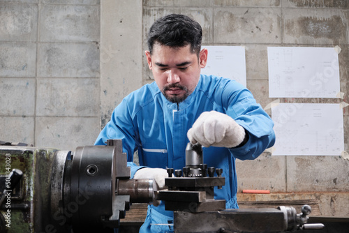 One professional Asian male industry engineer worker works in a safety uniform with metalwork precision tools, mechanical lathe machines, and spare parts workshop in the steel manufacturing factory.