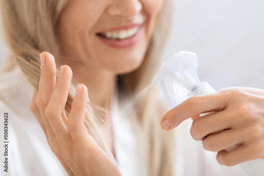 Cropped of blonde woman using hair spray Cropped of blonde woman using hair spray