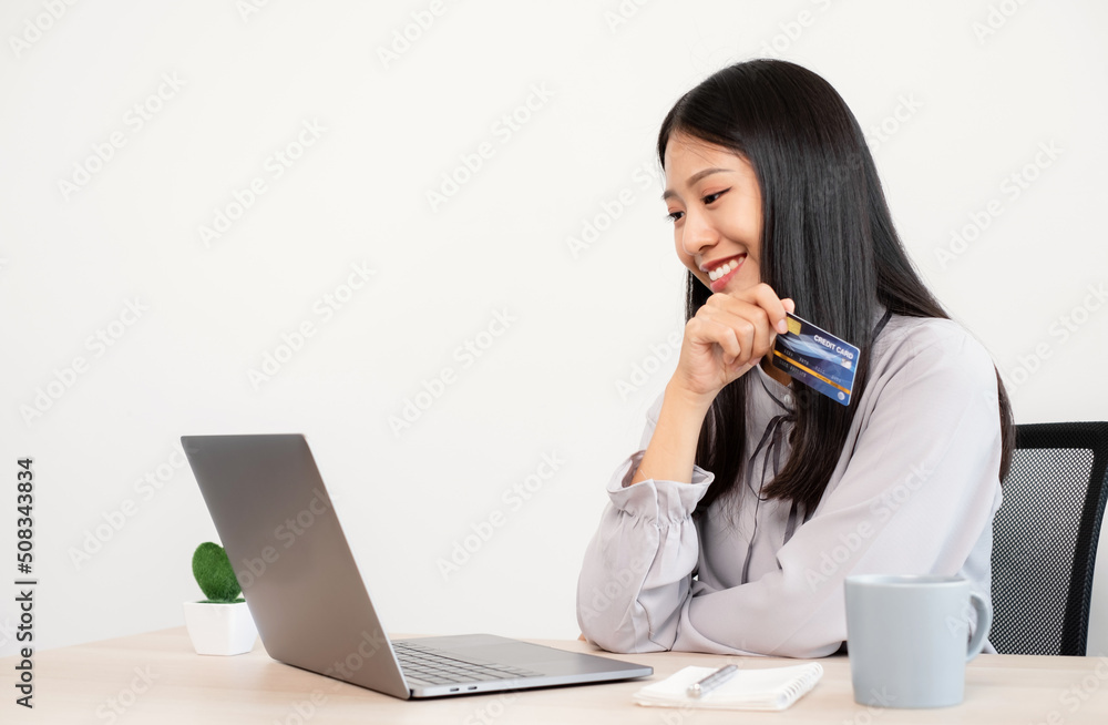 The Asian businesswoman's hand is holding a credit card and using a laptop for online shopping and internet payment in the office The Asian businesswoman's hand is holding a credit card and using a laptop for online shopping and internet payment in the office