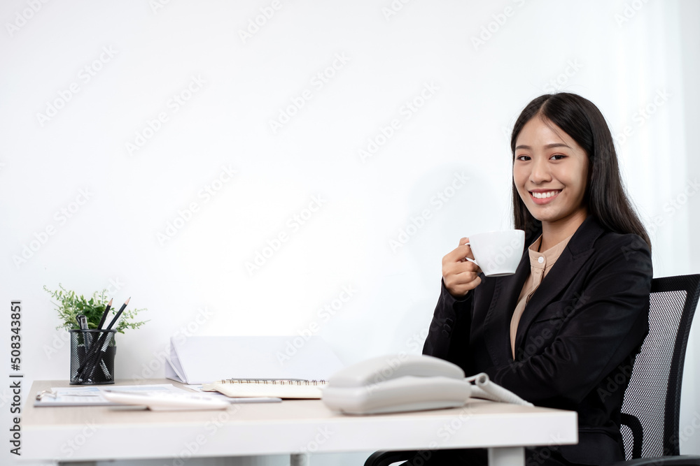 Asian businesswoman working on a laptop with a cheerful and happy smile while working at drink coffee the office Asian businesswoman working on a laptop with a cheerful and happy smile while working at drink coffee the office