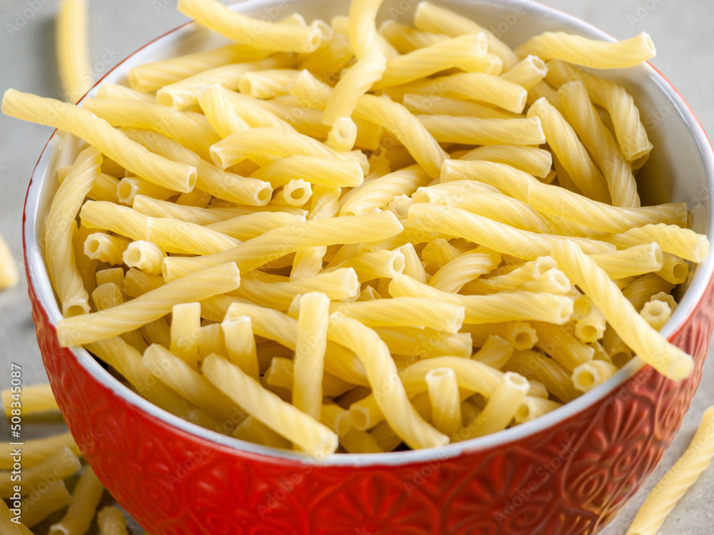 Closeup of Italian food yellow raw uncooked vermicelli, macaroni, noodle, pastry, pasta on the isolated bowl (close-up,meal, cuisine, cooking, gray, dry, dish, studio, plate,dinner, tile, cement) Closeup of Italian food yellow raw uncooked vermicelli, macaroni, noodle, pastry, pasta on the isolated bowl (close-up,meal, cuisine, cooking, gray, dry, dish, studio, plate,dinner, tile, cement)