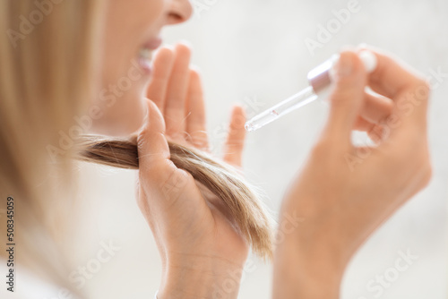 Cropped of blonde woman using hair oil