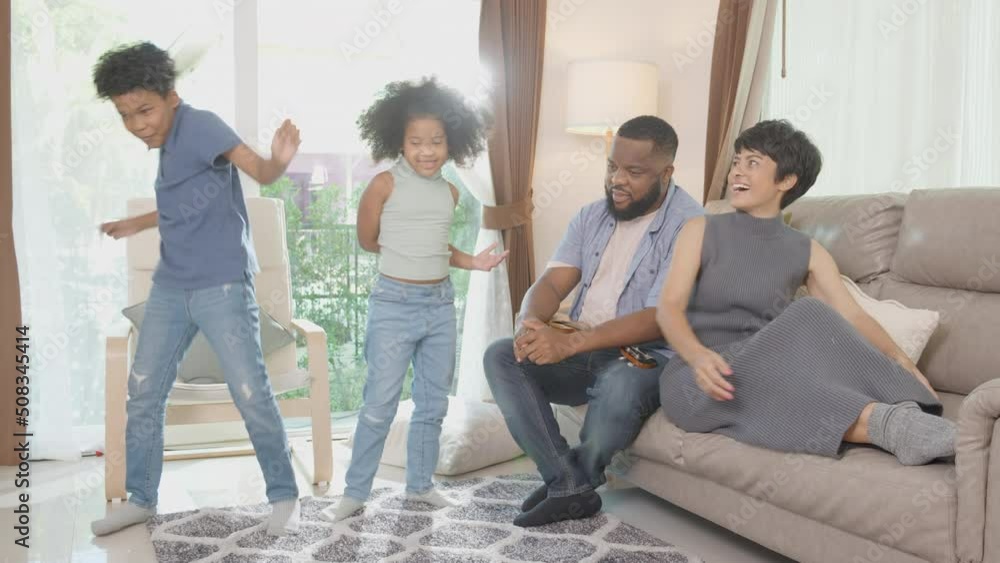 Happy family father playing ukulele or guitar and mother and children doing activity song and dancing together with fun and enjoy in the living room at home, hobby of parent and child for relax. Happy family father playing ukulele or guitar and mother and children doing activity song and dancing together with fun and enjoy in the living room at home, hobby of parent and child for relax.
