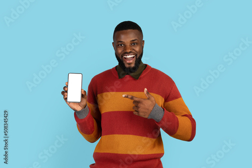Mobile Offer. Handsome black male pointing at telephone with empty white screen