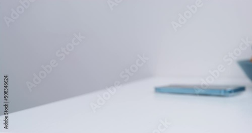 Man puts smartphone on white table taking away empty cup after drinking coffee. Male person takes mug to wash in kitchen at home close view