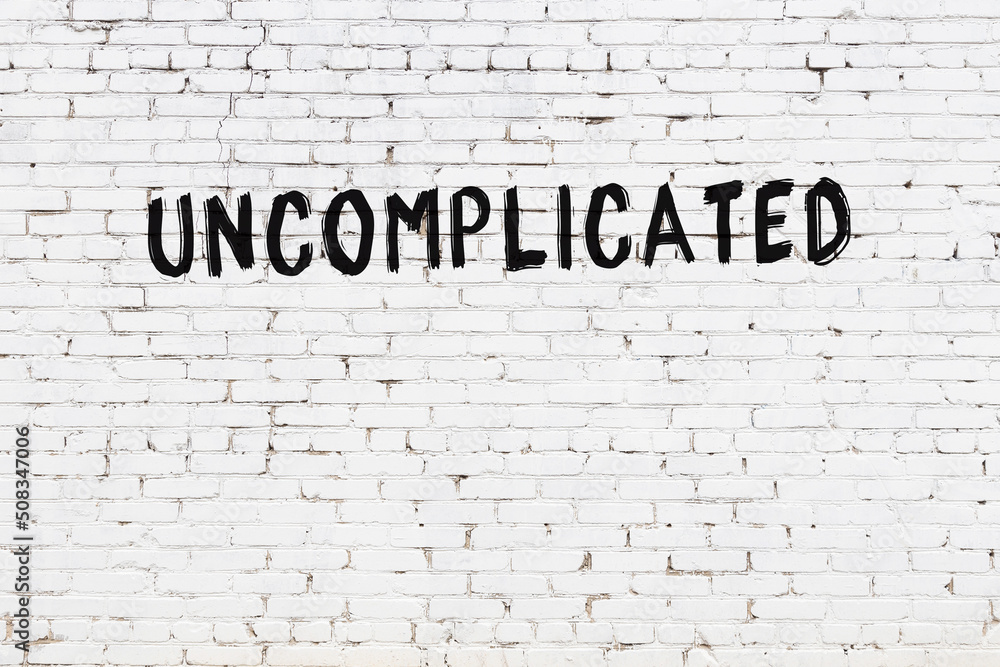 Inscription uncomplicated painted on white brick wall - obrazy, fototapety, plakaty 