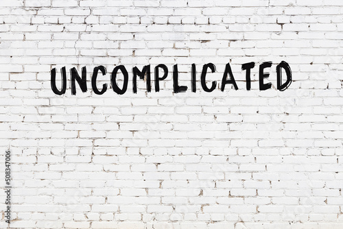 Inscription uncomplicated painted on white brick wall