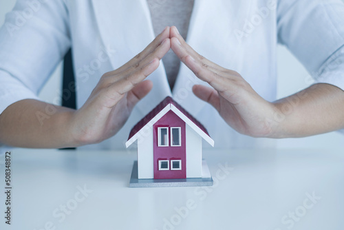 The hand of a real estate investment agent who protects the home design with lease documents, contracts for home purchase, home insurance, and purchase approvals for client