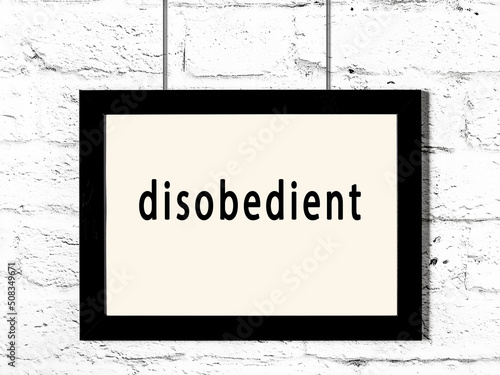 Foto Black frame hanging on white brick wall with inscription disobedient