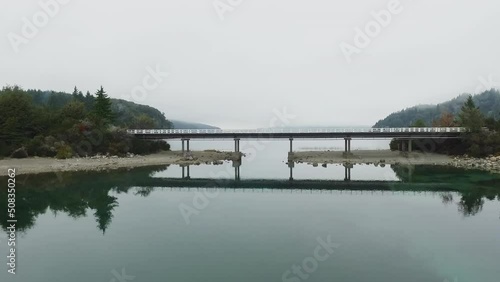 Wallpaper Mural Transport. Aerial view of the bridge and road across the turquoise water lake in an early cloudy morning with fog.The overpass is reflected in the water surface. Forest and mountains surroundings.  Torontodigital.ca