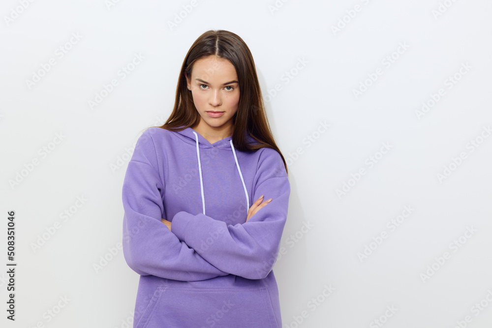 a tense woman stands on a white background in a purple tracksuit frowning forward with her arms crossed in front of her a tense woman stands on a white background in a purple tracksuit frowning forward with her arms crossed in front of her