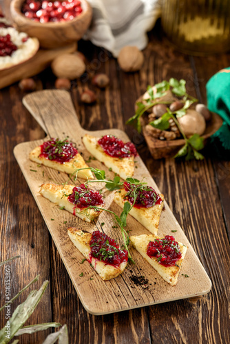 Hot appetizer for wine - grilled halloumi cheese with jam. Cheese appetizer baked halloumi on wooden background on rustic style. Adyghe cheese with berries dip on wooden table.