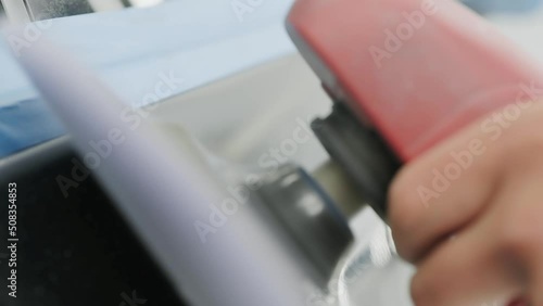 Worker polishing vehicle body with special grinder and wax from scratches at the car service station. Professional car detailing and maintenance concept.
