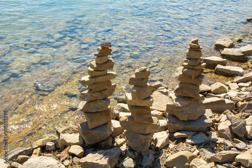 Rock cairn the art of stone balancing on a stone near a blue water flowing lake. Sunny day on the lake. A mood of calm and harmony with nature.