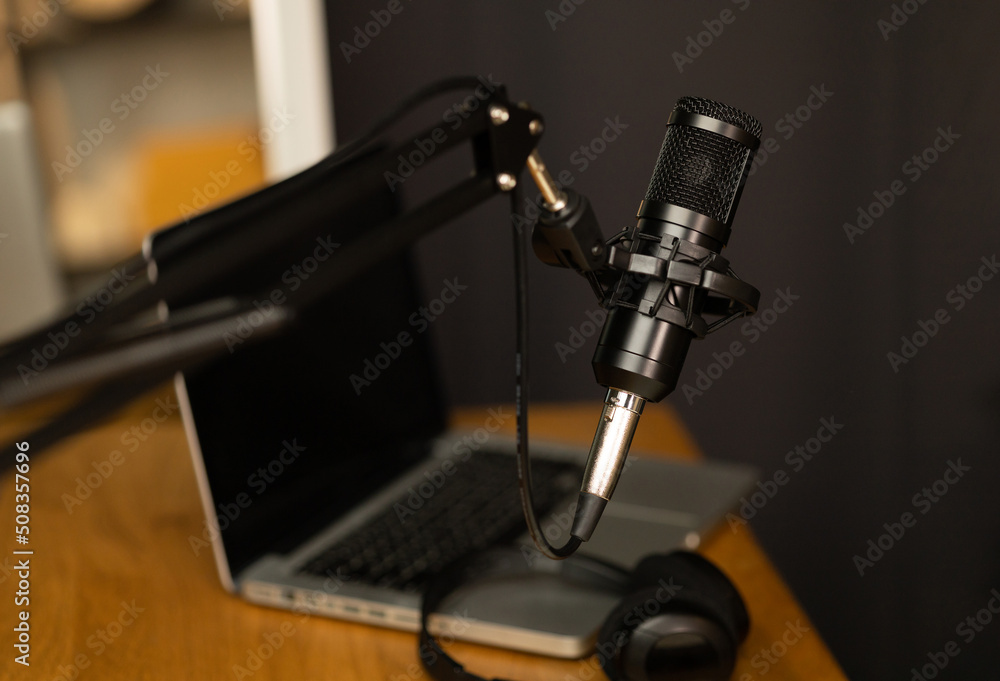 Desk of host streaming radio podcast at home broadcast studio.Such as laptop condenser microphone and headphone on table. Recording host streaming radio podcast interview conversation at home Desk of host streaming radio podcast at home broadcast studio.Such as laptop condenser microphone and headphone on table. Recording host streaming radio podcast interview conversation at home