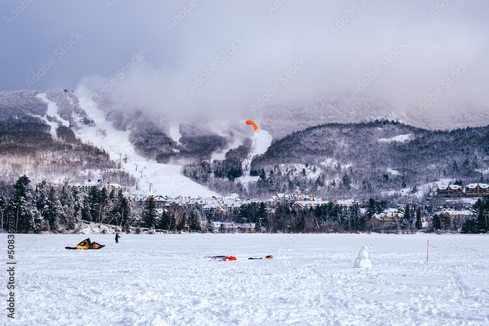 People snowkiting on a cold winter day on Lake Tremblant near Tremblant ski resort in Quebec (Canada) People snowkiting on a cold winter day on Lake Tremblant near Tremblant ski resort in Quebec (Canada)
