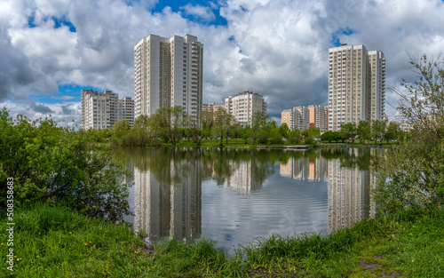 In the city park on the shore of the pond high-rise buildings