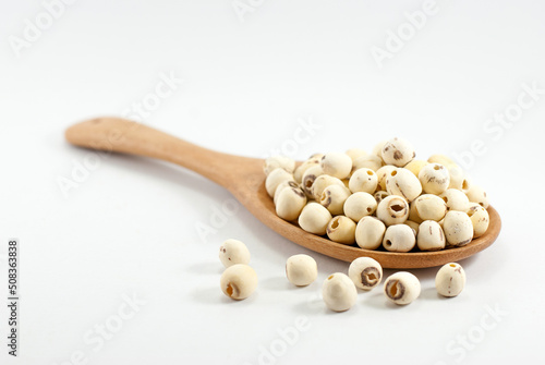 Dried lotus seeds in a wooden ladle and placed on a white floor, selective focus. photo