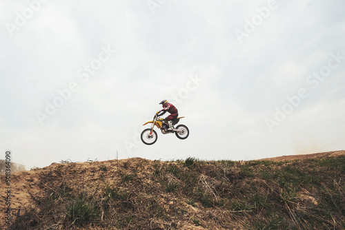 Jumping in air motorcyclist on  motocross motorcycle at the training ground photo