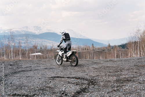 Fototapeta Naklejka Na Ścianę i Meble -  motorcyclist riding standing on dirt motorcycle on rubble at the top of off-road mountain