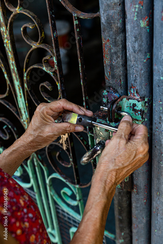 Grandma is unlocking the old house's iron leaking door.