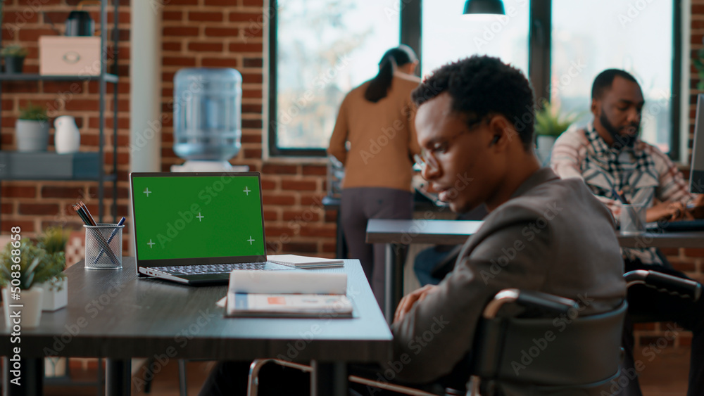 © DC Studio - Company employee analyzing greenscreen on laptop, working in disability friendly office. Businessman using chromakey background with isolated copyspace and blank mockup template.