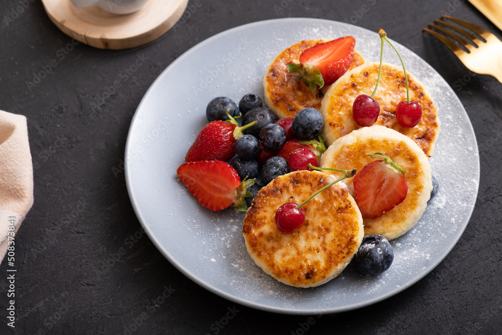 Roasted cheesecakes on a plate with powdered sugar and berries angle view Roasted cheesecakes on a plate with powdered sugar and berries angle view