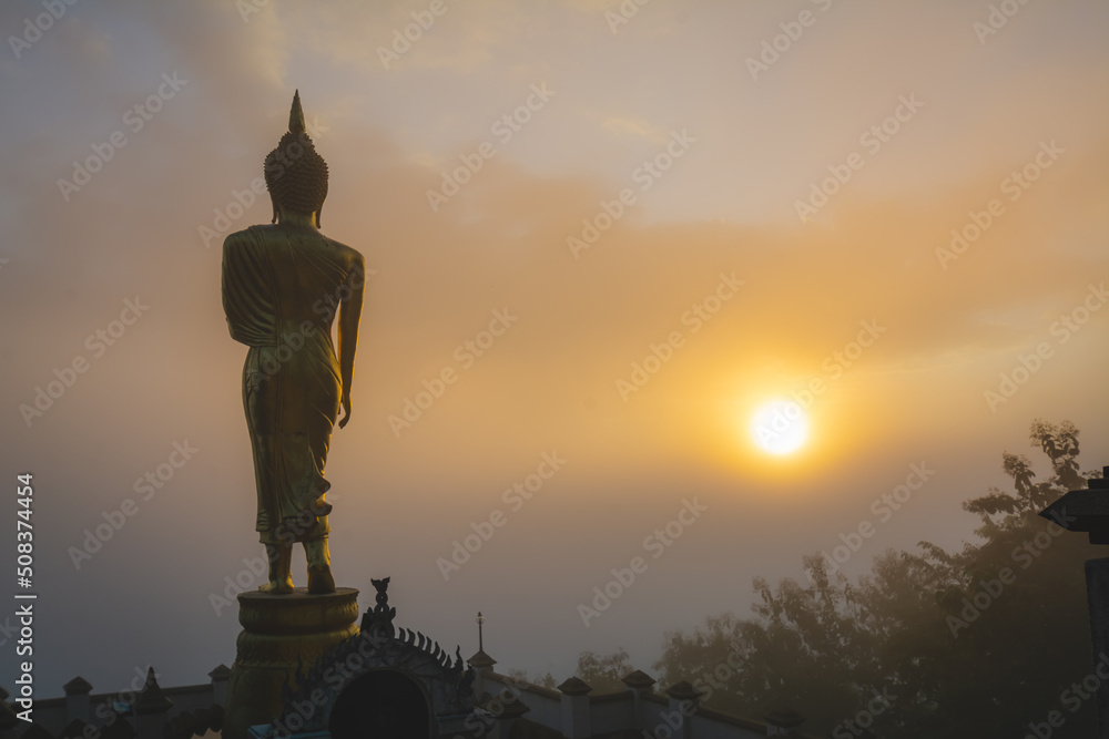 Fototapeta premium Golden Buddha statue in the morning at Wat Phra That Khao Noi, or Phrathat Khao Noi temple, is the top attraction with a fantastic view of Nan province, Thailand