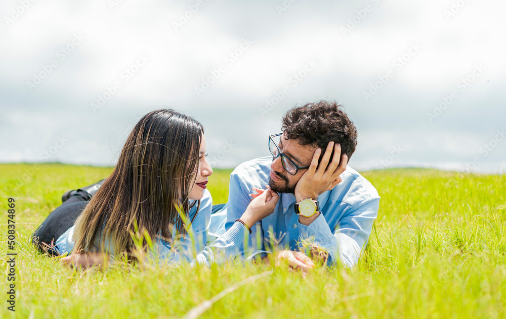 Two people in love lying on the grass looking at each other, A couple lying on the grass looking at each other, Young couple in love lying on the grass touching each other's faces Two people in love lying on the grass looking at each other, A couple lying on the grass looking at each other, Young couple in love lying on the grass touching each other's faces