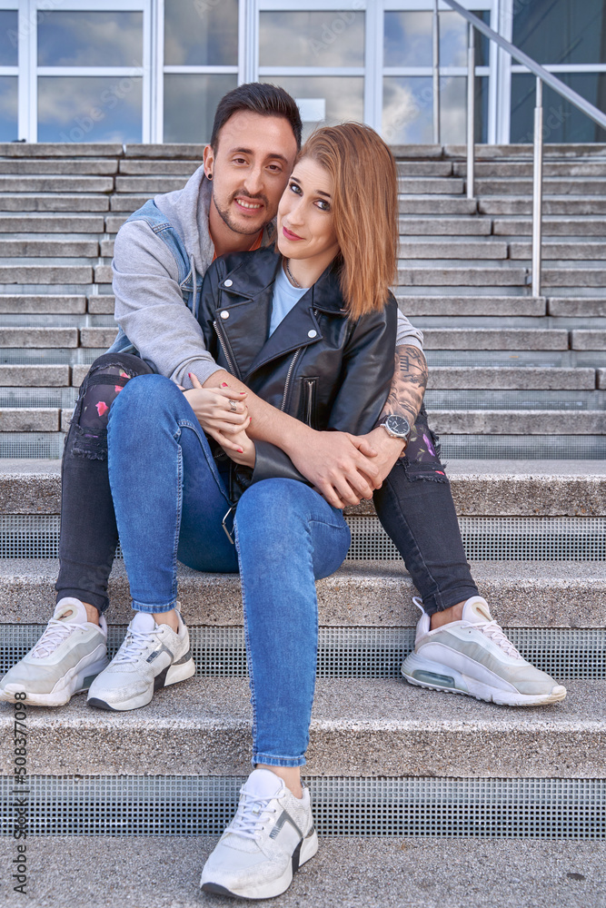 Man hugging his girlfriend while sitting on the stairs outdoors. Relationship and love concept. Man hugging his girlfriend while sitting on the stairs outdoors. Relationship and love concept.