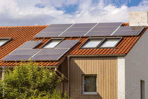 Solar Panel station on private House Roof. Solar panels on tiled roof with windows. 