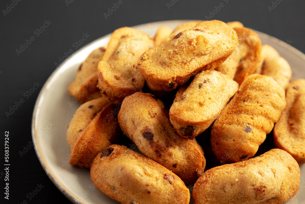 Homemade Chocolate Chips Madeleines on a Plate on a black background, side view. Close-up. Homemade Chocolate Chips Madeleines on a Plate on a black background, side view. Close-up.