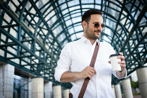 Casual dressed business man in front of office building, holding cup of coffe