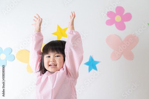手を挙げる笑顔の園児（子供・育児・子育て・保育園・幼稚園）