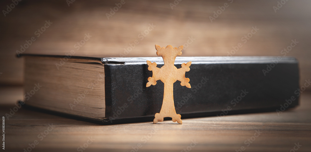 Christian cross and Bible on the wooden background.