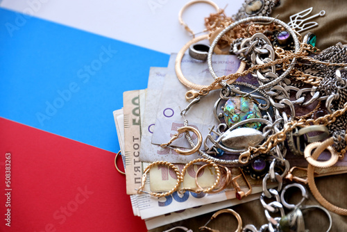 Obraz na płótnie Bunch of stolen jewelry and money on military uniform cloth fabric and russian flag