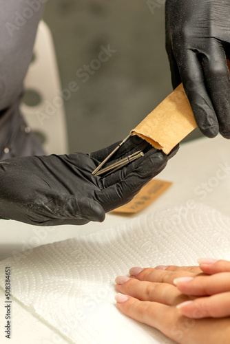 Manicure master takes out manicure tools from a kraft envelope in a nail salon