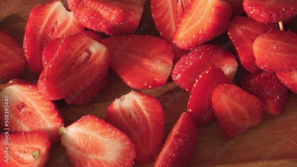 Fresh, red strawberries cut into slices lie on a wooden tray. Fresh, red strawberries cut into slices lie on a wooden tray.