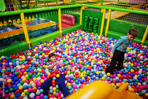 Child playing in colorful ball pit. Day care indoor playground. Balls pool for children. Kindergarten or preschool play room.