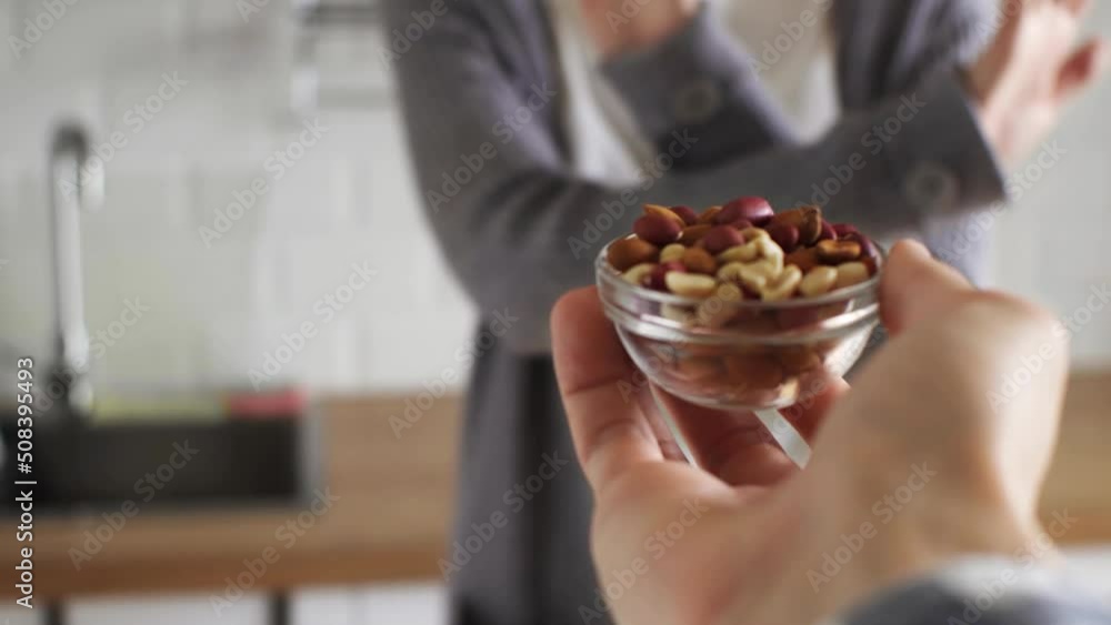 A man carries a plate of peanuts in his hand. A bowl of peanuts