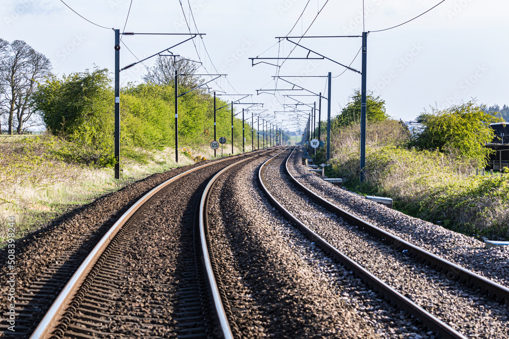 East Coast of England railway line with tracks curving, overhead line equipment and railway signs