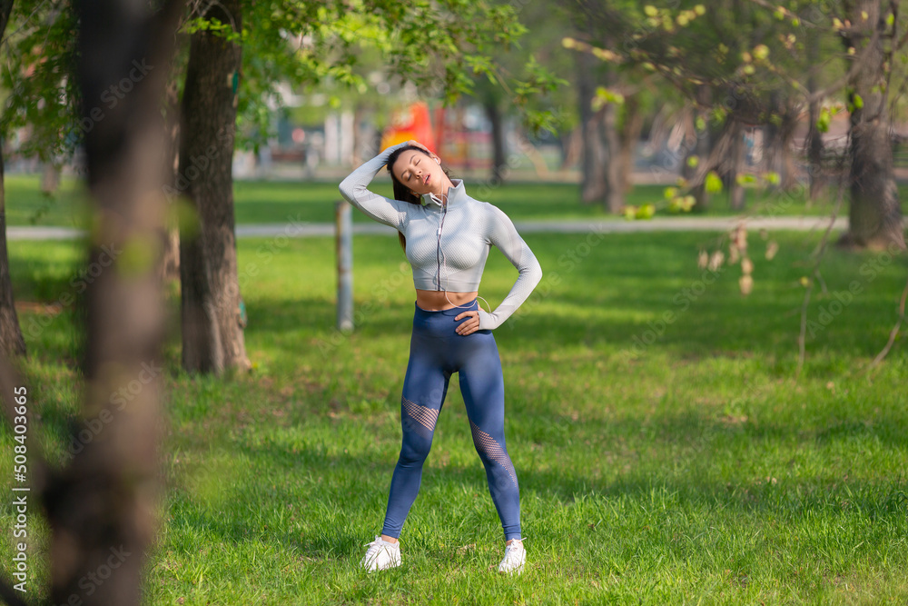 Photo of a woman stretching neck - warming up before running or working out. Female runner stretching arms before running at morning. Photo of a woman stretching neck - warming up before running or working out. Female runner stretching arms before running at morning.