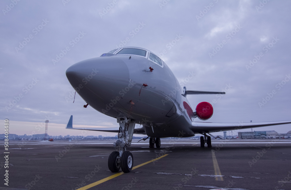 Private jet parked at the airport with engine plugs on against a cloudy sky Private jet parked at the airport with engine plugs on against a cloudy sky