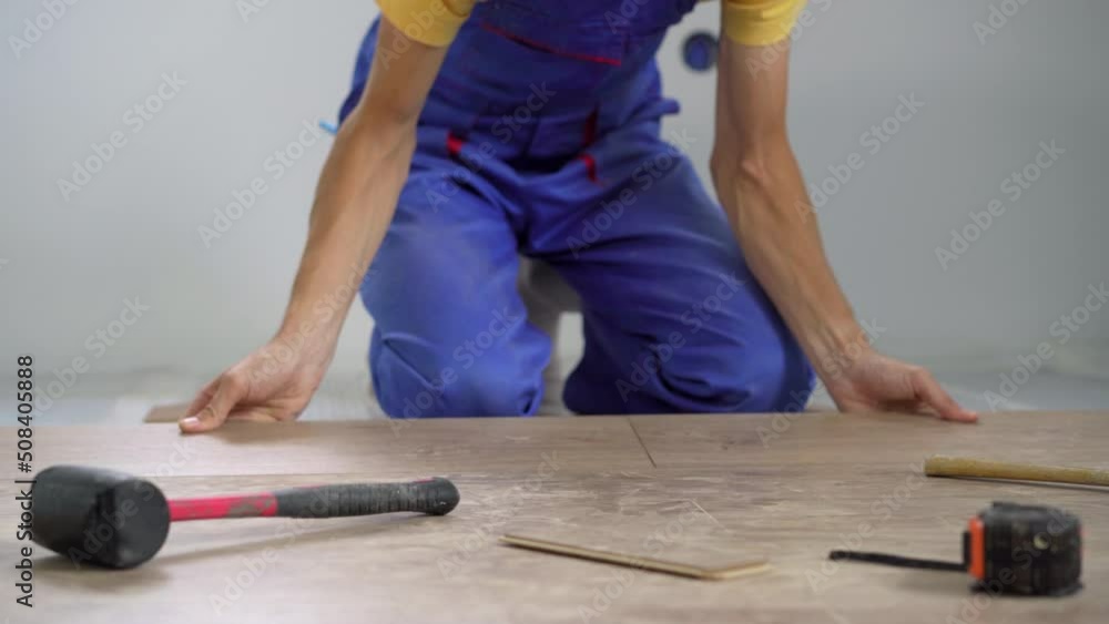 A man professional laminate installer laying laminate wood A man professional laminate installer laying laminate wood